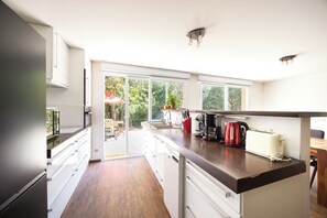 A modern kitchen with a large island, built-in appliances, and a view to the outside.