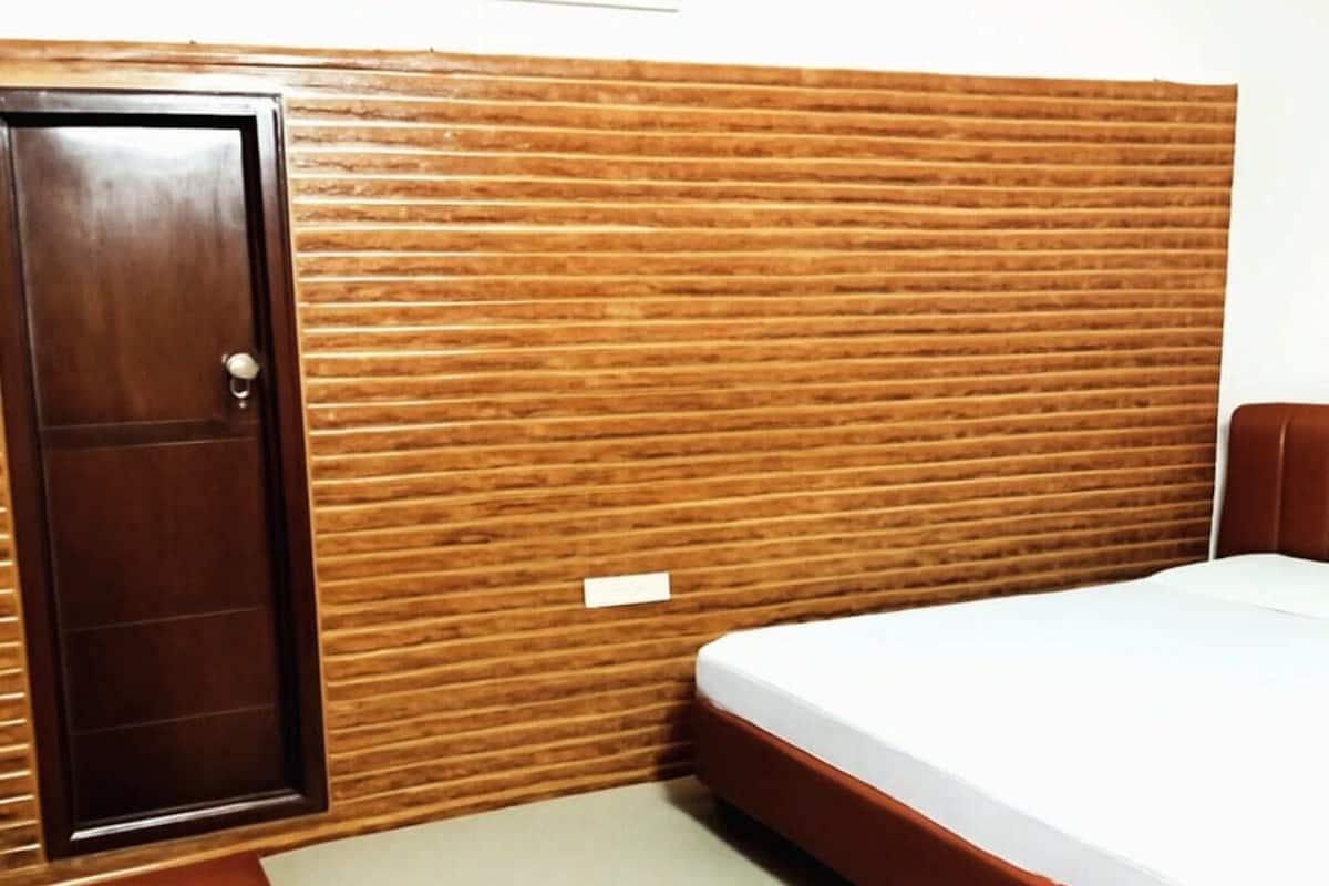 A room with a wooden headboard, a bed, and a bench.