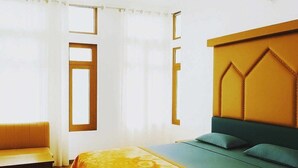 Un dormitorio con cama, un banco y una ventana con cortinas.