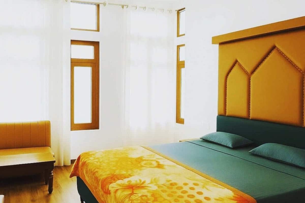 A bedroom with a bed, a bench, and a window with curtains.
