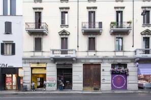 A row of buildings with shops on the ground floor, including a visible storefront with a sign that reads "Carmelli". - Easylife - Contemporary design in Porta Sempione (Milano)