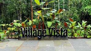 A sign reading "Village Vista" amidst lush greenery.