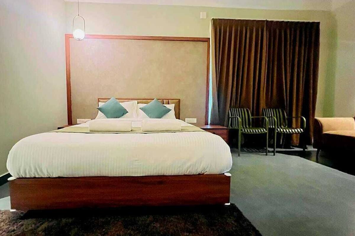 Een hotelkamer met een groot bed, een houten hoofdbord, een nachtkastje, een stoel en een bank.