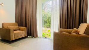 A room with two brown armchairs and a large sliding glass door leading to a garden.