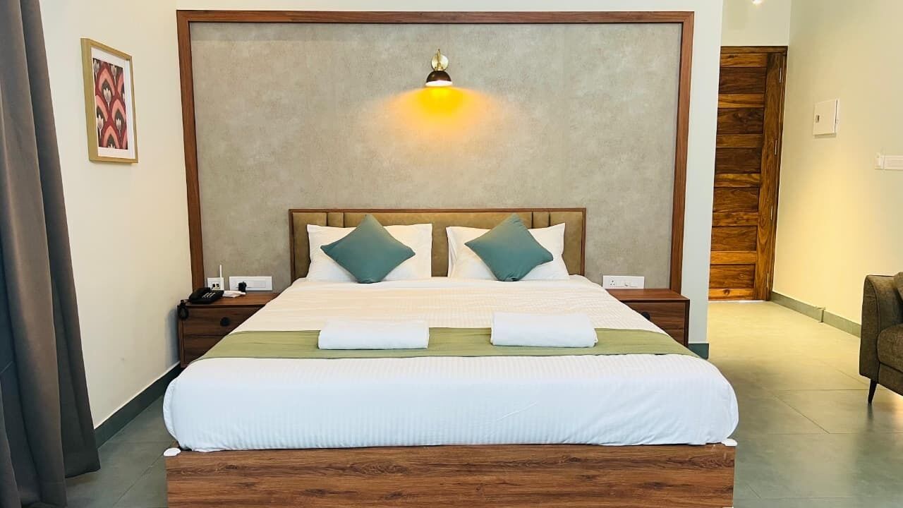 A neatly made bed with a wooden headboard, two pillows, and a bedside table with a lamp.