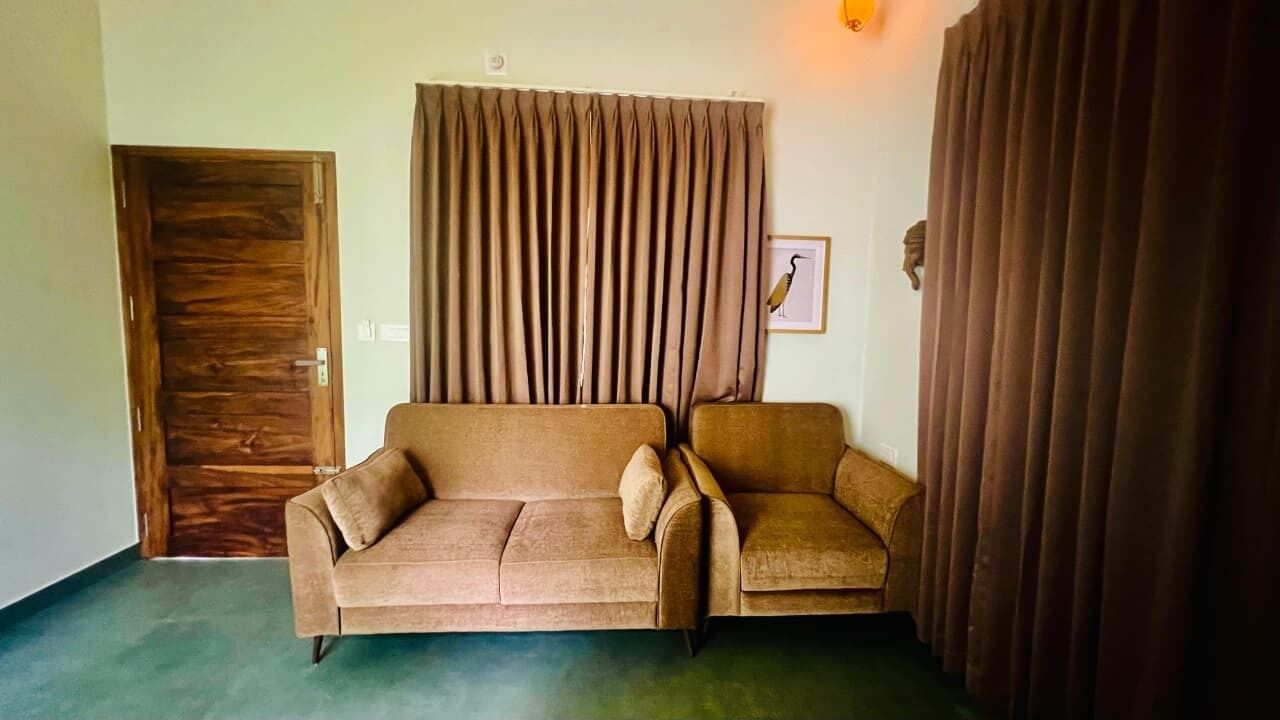 A room with a brown sofa, a wooden door, and a curtain.