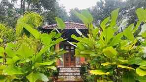 A traditional house with a tiled entrance and a red roof, surrounded by lush greenery. - The Village Vista (Sulthan Bathery)