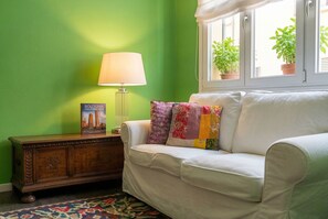 A room with a green wall, a white sofa with colorful pillows, a wooden side table, a lamp, and a window with potted plants. - Green House Bologna City Center
two double bedrooms with en suite bathrooms (Bologna)