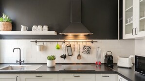 A modern kitchen with a black countertop, white cabinets, a stainless steel sink, and a microwave.