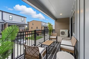 A balcony with outdoor furniture, a view of neighboring buildings, and an air conditioning unit. - The Lockwood Loft | Modern 2BR Townhome w/ Garage (North Kansas City)
