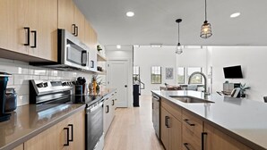 A modern kitchen with stainless steel appliances, wooden cabinets, and a large island with a sink.