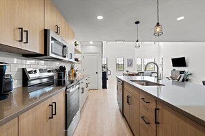 A modern kitchen with stainless steel appliances, wooden cabinets, and a large island with a sink.