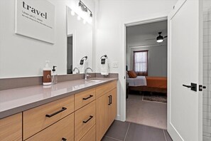 Ein modernes Badezimmer mit großem Spiegel, Waschtisch und Handtuchhalter.