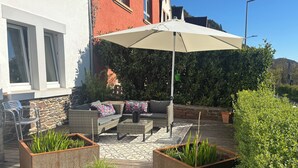 An outdoor patio with a wicker sofa, a table, and planters.