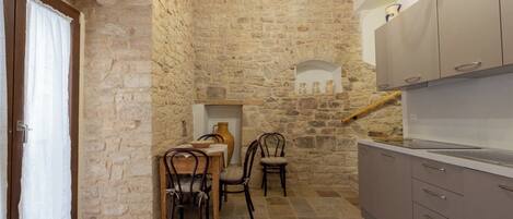 Une cuisine aux murs en pierre, une table à manger avec des chaises et des meubles de rangement modernes.
