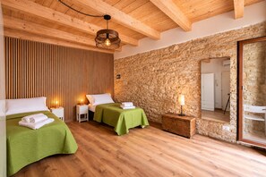 A hotel room with two beds, wooden floors, a stone wall, and a wooden ceiling. - PALAZZO RIZZI DIMORA DEI TEMPLARI (Bitetto)