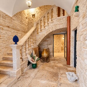 A stone staircase with a wooden handrail, a green vase with dried plants, and a large ceramic pot. - PALAZZO RIZZI DIMORA DEI TEMPLARI (Bitetto)