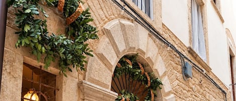 A stone building with a large arched entrance, a number '24' sign, and greenery decorating the entrance.