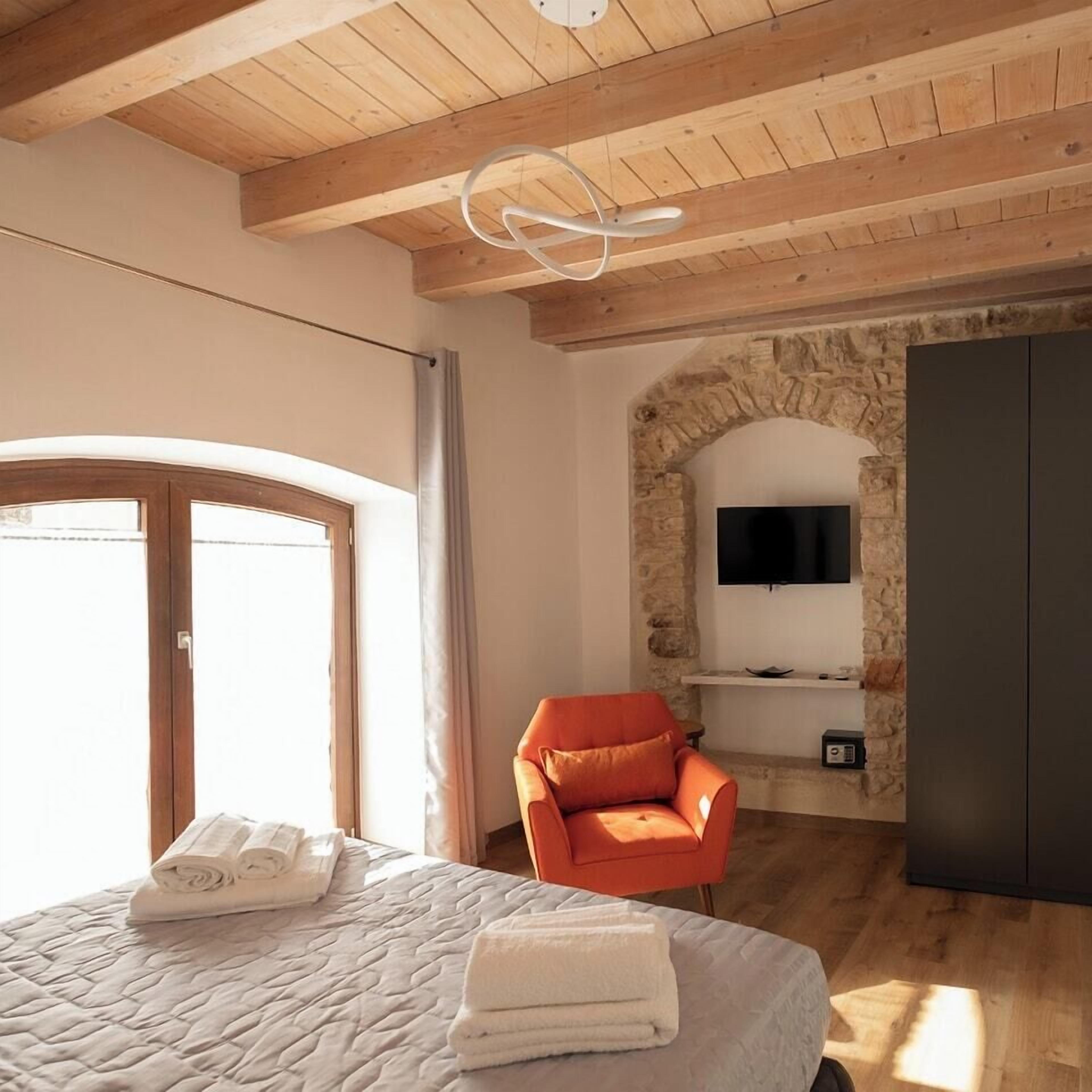 A bedroom with a bed, a stone arch wall, a television, and a wardrobe.