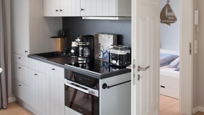A compact kitchen with white cabinetry, a black countertop, and a built-in oven. - Comfortable vacation apartment Meertied in the Lindenhof on Wangerooge with balcony (Wangerooge)