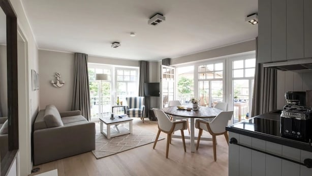 A modern kitchen with a dining area, a sofa, and a TV. - Comfortable vacation apartment Meertied in the Lindenhof on Wangerooge with balcony (Wangerooge)