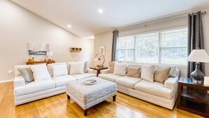 A modern living room with a sectional sofa, a coffee table, and a large window with curtains.