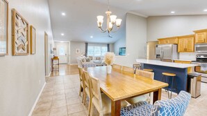 A spacious kitchen with modern appliances, a dining area with a wooden table and chairs, and a chandelier.