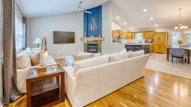 A modern living room with a sofa, a glass coffee table, a TV, and a fireplace.