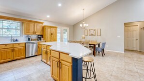 A spacious kitchen with wooden cabinets, a large island, and a dining area with a chandelier.