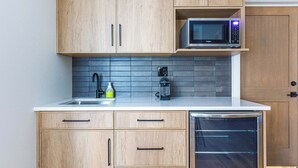 A modern kitchen with wooden cabinets, a microwave, a coffee maker, and a dishwasher. - Aurora Lite - Brand new suite with private entrance (Canmore)