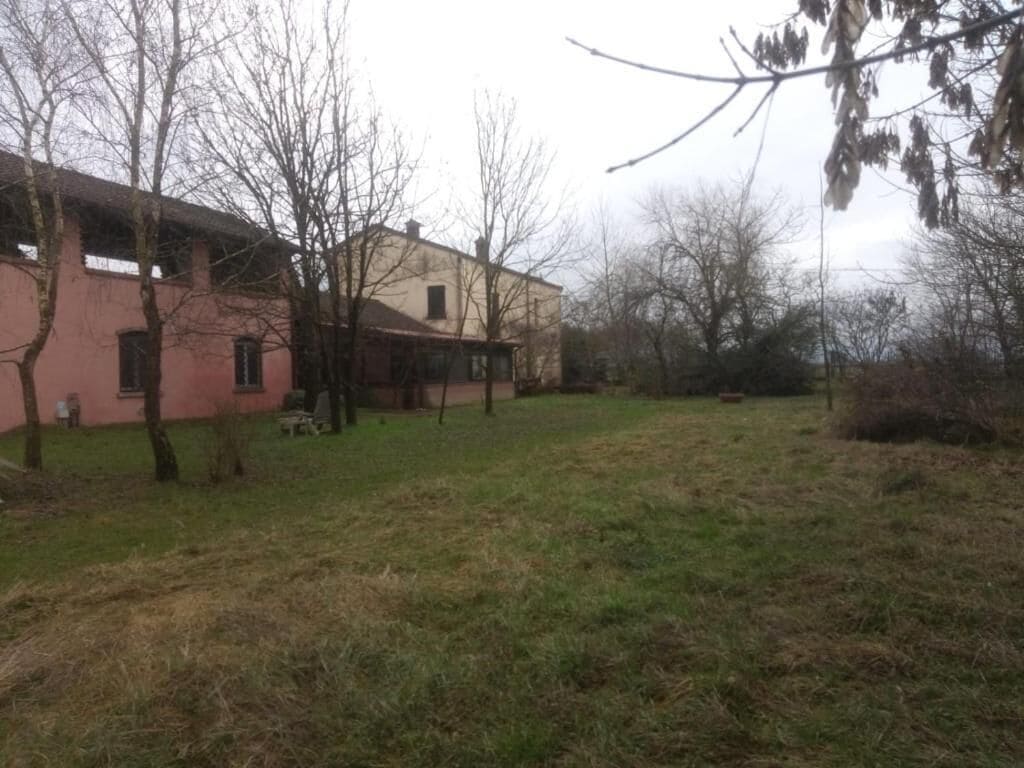 Un edificio con fachada rosa, un patio con césped y árboles sin hojas.