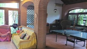 Una habitación con un arco de ladrillo, una mesa de ping pong, un sofá y una ventana con vistas a la vegetación.