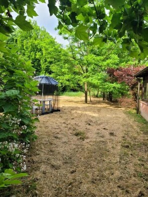 A garden with a gazebo, trees, and a wooden structure. - B&B ARCADIA (Casanova Lonati)