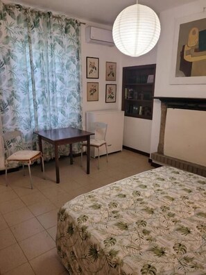 A room with a bed, a desk, a chair, a bookshelf, and a painting on the wall. - B&B ARCADIA (Casanova Lonati)