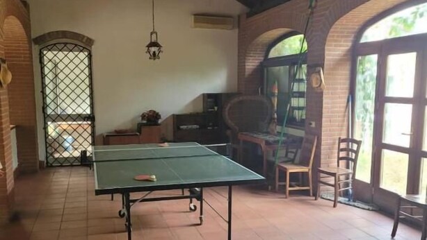 Una habitación con mesa de ping pong, una silla de madera y ventana con vistas.