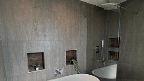 A modern bathroom with a freestanding bathtub, a glass-enclosed shower, and a large mirror.