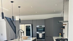A modern kitchen with grey cabinets, a white countertop, and stainless steel appliances.