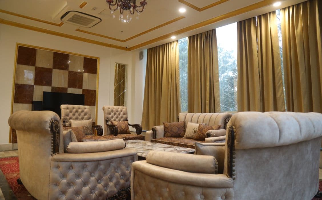 A spacious living room with a large sofa set, a television, and a chandelier.