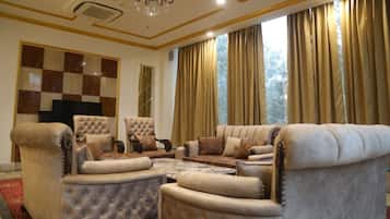 A spacious living room with a large sofa set, a television, and a chandelier.