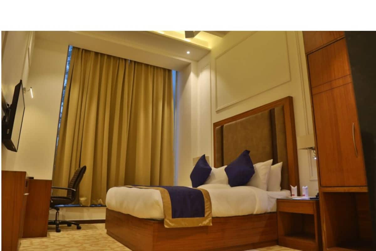 Quarto de hotel com cama, escrivaninha, cadeira e guarda-roupa.