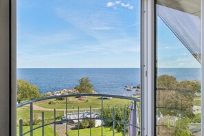 Ein Balkon mit Blick auf das Meer, eine Rasenfläche und ein Gebäude in der Ferne.