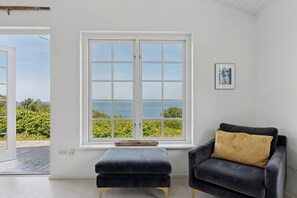 A room with a large window, a dark armchair, and a small ottoman.