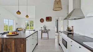 Een moderne keuken met een centraal eiland, houten kastjes en hanglampen.