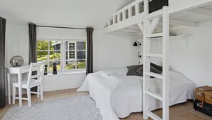 Een slaapkamer met een stapelbed, een bureau en een stoel.