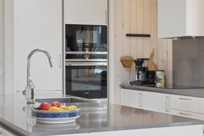 A modern kitchen with a stainless steel sink, a Siemens oven, and a coffee maker on the counter.