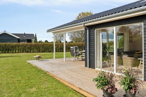 A modern house with a wooden deck, a covered patio, and a large sliding glass door.