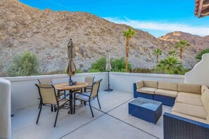 An outdoor patio with a table and chairs, a sofa, and an umbrella.