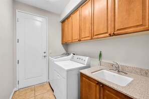 A laundry room with a washing machine, a dryer, and a sink.