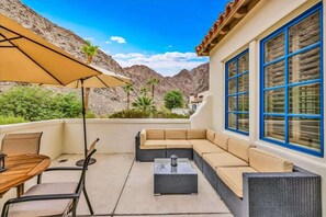 A patio with a sofa, table, chairs, and an umbrella.