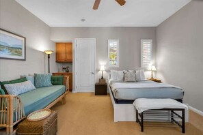 A bedroom with a bed, a sofa, a nightstand, a lamp, a window, and a door.